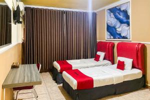 a hotel room with two beds and a table at RedDoorz Syariah At Hotel Matahari 1 Jambi in Jambi +6 photos