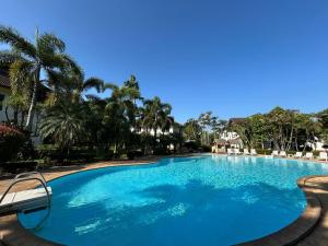 a large blue swimming pool with palm trees at Teak Garden Resort, Chiang Rai in Chiang Rai