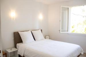 a bedroom with a white bed with a window at La villa Cigaliere in Tulette