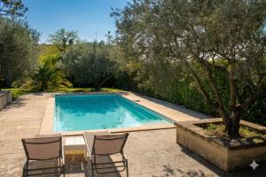 a swimming pool with chairs and a table and a tree at La villa Cigaliere in Tulette