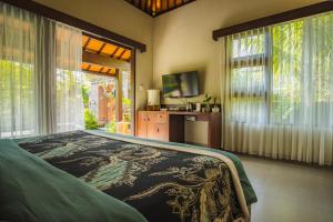 a bedroom with a bed and a tv and windows at K Ko Surf Village at Keramas in Lebih