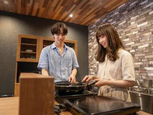 a man and a woman preparing food in a kitchen at YuiLocalZao in Zaō Onsen