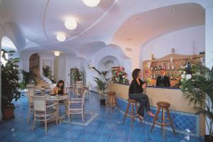 two women sitting at a bar in a restaurant at Hotel Terme Saint Raphael in Barano d'Ischia