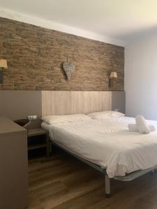 a bedroom with a bed and a brick wall at Hostal La Cabanya in Setcases