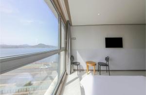 a room with a large window and a table and chairs at Sunrise Hotel Seongsan in Seogwipo