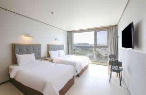 a hotel room with two beds and a television at Sunrise Hotel Seongsan in Seogwipo