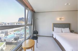 a bedroom with a bed and a large window at Sunrise Hotel Seongsan in Seogwipo