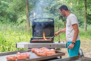 a man is cooking food on a grill at La Parenthèse Meslandaise in Mesland