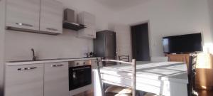 a kitchen with white cabinets and a table and a tv at Alloggio Tobia in Biella
