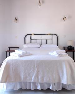 een wit bed met witte lakens en handdoeken erop bij Sigrion Villas in Sígrion