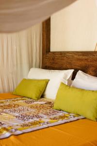 a bed with two green pillows on top of it at Fare Teiti Beach Bungalow in Haapiti +8 photos