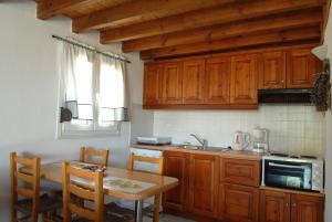 een keuken met houten kasten, een tafel en een wastafel bij Sigrion Villas in Sígrion