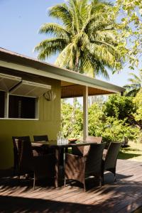 a table and chairs on a deck with a palm tree at Fare Teiti Beach Bungalow in Haapiti