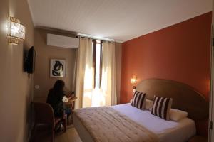 a woman in a hotel room with a bed and a window at Boutique Hôtel Azur in Marseille +126 photos