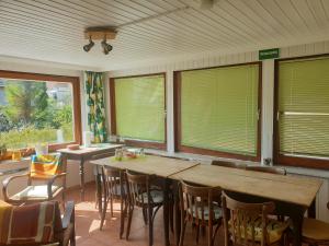 a dining room with a table and chairs and windows at Ferienhaus am DEISTER in Barsinghausen