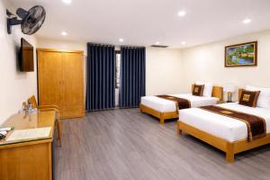 a hotel room with two beds and a desk at Hoa Cương Hotel 2- Hà Giang in Ha Giang