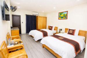 a hotel room with two beds and a television at Hoa Cương Hotel 2- Hà Giang in Ha Giang