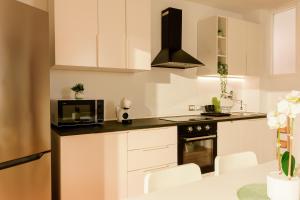 a kitchen with white cabinets and a microwave at SHARED SWIMMING POOL, House relax Lu Bagnu in Castelsardo +18 photos