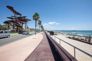 a sidewalk next to a beach with people and the ocean at Apartment La Turquesa in La Pineda