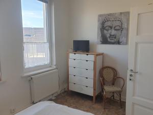 a bedroom with a dresser and a chair and a window at Ferienhaus am DEISTER in Barsinghausen