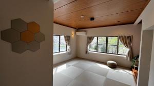 an empty room with windows and a wooden ceiling at SAKADONEguesthouse in Iijima