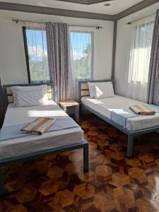 two beds in a room with two windows at D Estelita Guest House in Moalboal