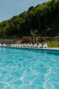 a swimming pool with white chairs and a mountain at LPM Sporthotel Durbuy in Durbuy