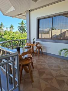 a balcony with tables and chairs and a large window at D Estelita Guest House in Moalboal