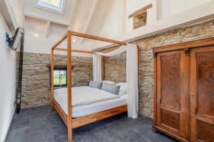 a bedroom with a canopy bed and a stone wall at Glamorous Cottage mit Kamin und Sauna in Dahlem