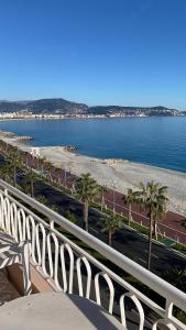 a balcony with a view of a beach with palm trees at Un balcon sur la mer in Nice