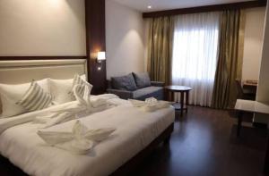 a hotel room with a large white bed and a chair at Hotel Regalia in Bathinda +19 photos