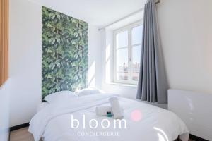 a white bedroom with a bed with a window at Le Soleil du Marché central in Nancy
