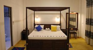 a bedroom with a canopy bed with yellow and blue pillows at Sweden Inn Guesthouse in Hikkaduwa
