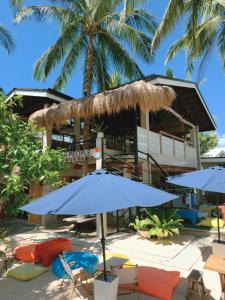 a resort with chairs and umbrellas and palm trees at Beach People Hostel Bantayan Island in Ocoy