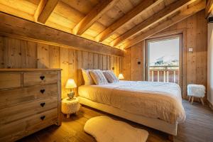 a bedroom with a bed and a large window at Chalet Cocoon in Combloux