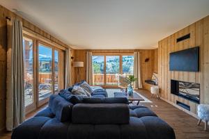 a living room with a large blue couch and a television at Chalet Cocoon in Combloux