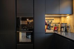 a kitchen with black cabinets and an oven at Chalet Cocoon in Combloux
