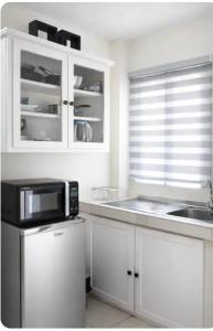a white kitchen with a microwave and a sink at PINK POUI Spaces Vacation Rentals in Arima