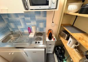 a small kitchen with a sink and a microwave at Studio Cosy Carnot in Compiègne