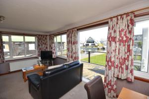 a living room with a couch and large windows at Kingfisher Lodge in Wroxham