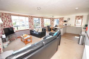 a living room with a leather couch and a kitchen at Kingfisher Lodge in Wroxham