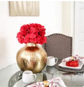 a vase with red flowers in it on a table at PINK POUI Spaces Vacation Rentals in Arima