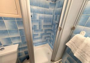 a blue tiled bathroom with a shower and a toilet at Studio Cosy Carnot in Compiègne