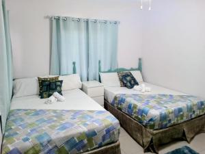 two beds in a room with blue curtains at Summer Breeze Villa in Lucea +17 photos
