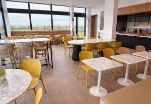a dining room with tables and yellow chairs at B&B HOTEL Rennes Liffré in Liffré