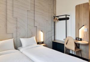 a bedroom with two beds and a desk and a chair at B&B HOTEL Rennes Liffré in Liffré