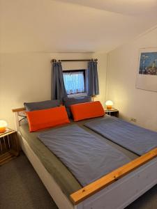 a bedroom with a large bed with two orange pillows at Hotel Katerberg - Room and Kitchen in Ahlefeld