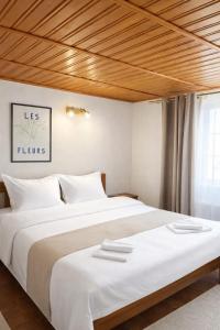 a bedroom with a large white bed with a wooden ceiling at Heaven Boutique in Pucioasa