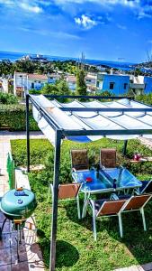 a picnic table and chairs under a canopy with a grill at Villa Infinity View Athens Riviera in Anavyssos
