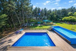 a large swimming pool with a wooden deck next to a yard at Taean Red Balloon Pension in Taean +9 photos